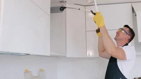 Installation of upper kitchen cabinets. A happy smiling repairman in the kitchen Stock Footage 130452589