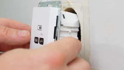 Installation of a USB Type-C socket at the head of the bed for charging devices. Stock Photos