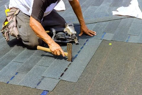 An installation worker using an air pneumatic nail gun installed new bitumen Foto stock