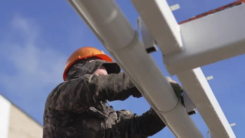 Installer anchors gutter pipe onto metallic support Video stock 306416278