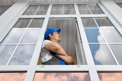 Installer plastic windows stands open window with his hands folded on his ches Stock Photos