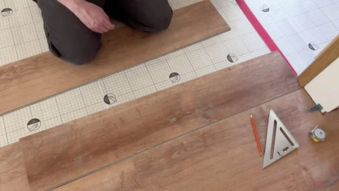 Installer positioning planks on underlayment Stock Footage 321691955