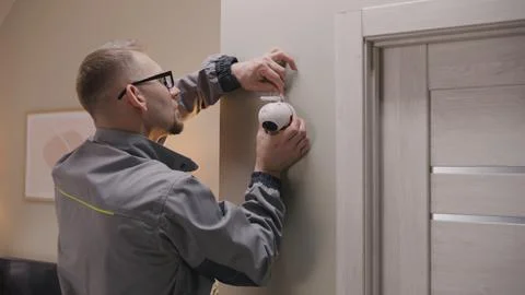 Installer puts security camera on wall mount Stock Photos