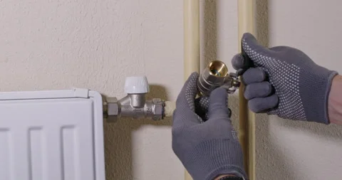 Installer tests fit ball valve to radiator tee before install Stock Footage 322010297