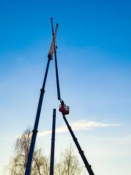 Installing the antenna on a blue sky background. Worker connects two metal .. Stock Photos