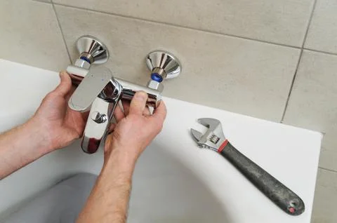 Installing bath faucet. Stock Photos