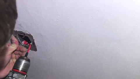 Installing a ceiling light fixture in a living room with a drill and electrical Vídeo Stock 326377525