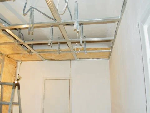 Installing ceiling metal frame with U-shaped brackets and mineral wool insu.. Stock Photos