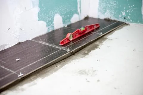 Installing ceramic floor tiles - measuring and cutting the pieces, closeup Stock Photos