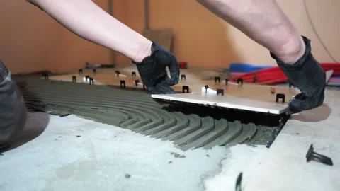 Installing ceramic floor tiles placing the tile into the adhesive material Stock-Footage 152241619