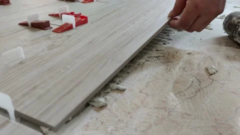 Installing ceramic floor tiles - placing the tile into the adhesive material Stock Footage 153162894