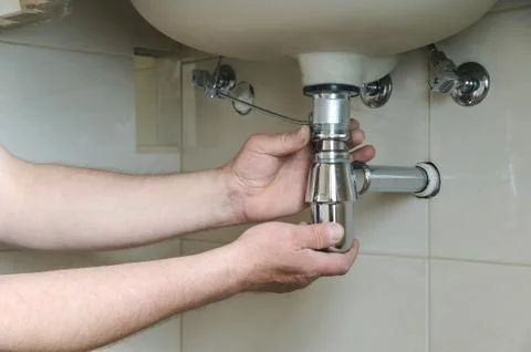 Installing a chrome basin sink bottle trap waste. Stock Photos