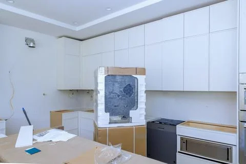 Installing custom kitchen cabinet in white color in newly constructed home Stock Photos