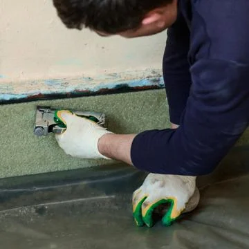 Installing damping tape with a stapler, close up of repair work in the house. Stock Photos