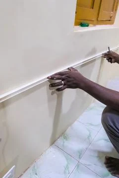 Installing decorative trim on a wall in a home setting Stock Photos