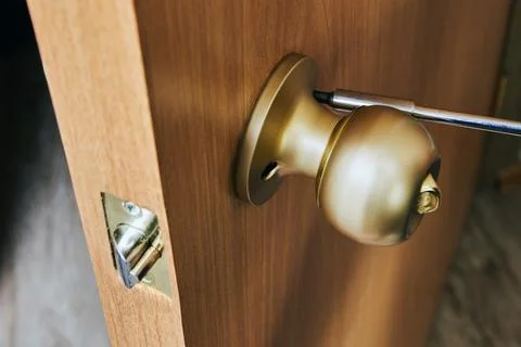 Installing door handle with lock and latch,  locksmith tightens mounting scre Stock Photos
