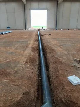 Installing drainage pipes inside new industrial building foundation 스톡 사진
