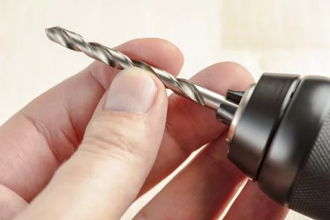 Installing a drill bit in a drill, hands take a drill and install it in a Stock Photos