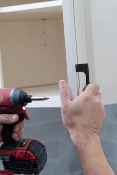 The installing a furniture handle process of assembling cabinet Stock Photos