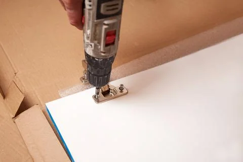 Installing a furniture hinge on a door, assembling furniture and fastening .. 库存照片