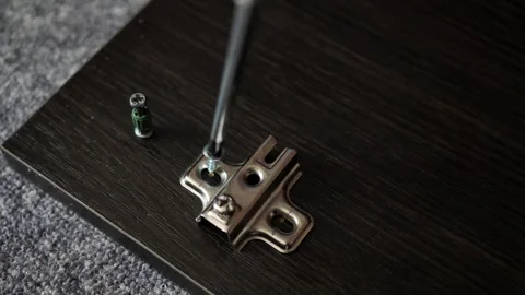 Installing hinges on a furniture door using a Phillips screwdriver. Stock Footage 286140271