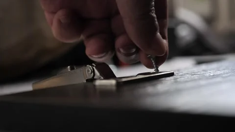 Installing hinges on a furniture door using a Phillips screwdriver. furniture Stock Footage 287615097