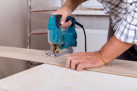 Installing laminate flooring. Carpenter cut parquet floor board with electric Stock Photos