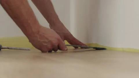 Installing laminate plank over yellow underlayment near wall Vidéo 346159810