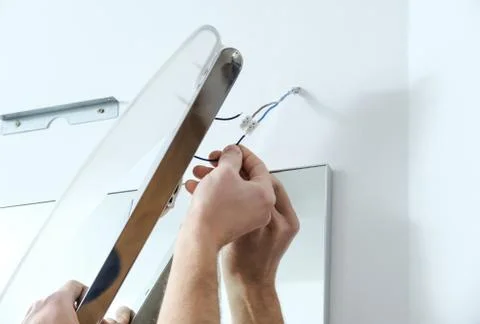 Installing the lamp above the mirror. Stock Photos