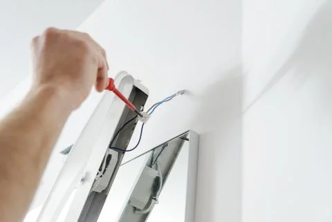 Installing the lamp above the mirror. Stock Photos