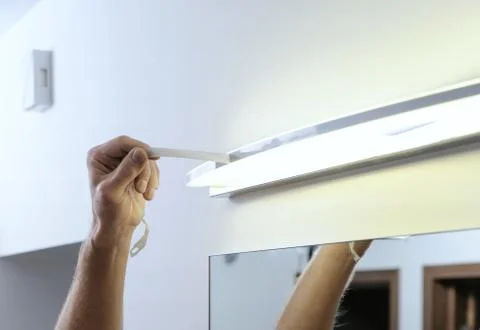 Installing the lamp above the mirror. Stock Photos