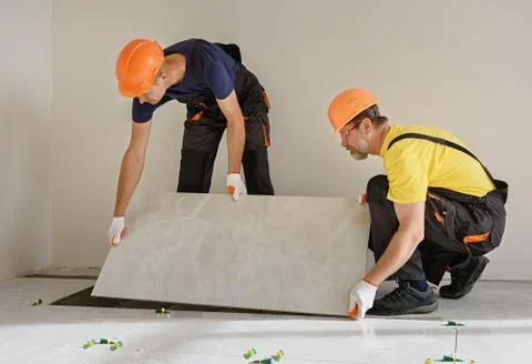 Installing a large ceramic tile. Stock Photos