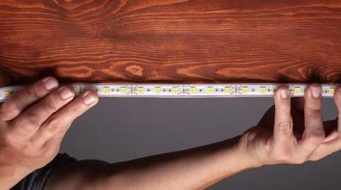 Installing led strip lighting for under wooden table. Stock-Fotos