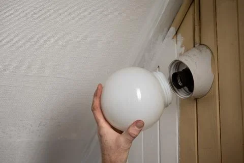 Installing light bulb in wall lamp at home Stock Photos