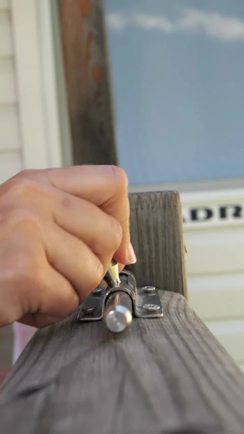 Installing a metal slide bolt latch on a weathered wooden gate Stock Footage 342520094