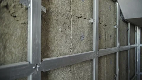 Installing mineral wool in metal frames on wall Stock Footage 201382587