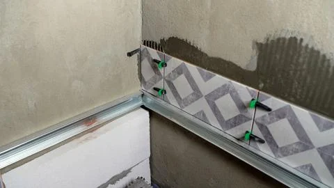 Installing patterned ceramic tiles on concrete wall using adhesive and gree.. Foto stock