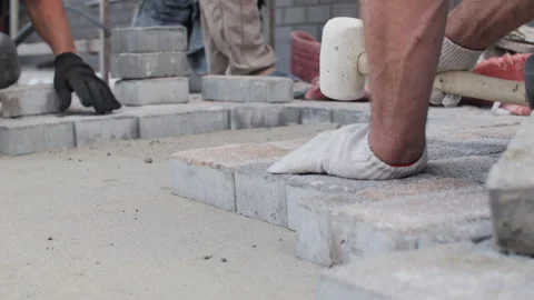 Installing paving stones with rubber mallet on construction site Stock Footage 311591975