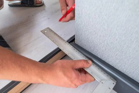 Installing a plinth in the room, measuring the required length using a square Fotos de archivo