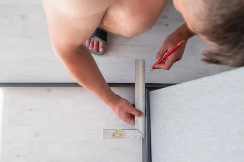 Installing a plinth in the room, measuring the required length using a square Fotos de archivo