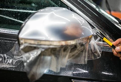 Installing PPF on the mirror of the car. Stock Photos