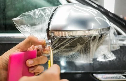Installing PPF on the mirror of the car. Stock Photos