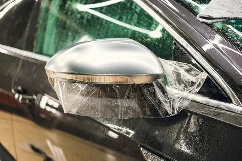 Installing PPF on the mirror of the car. Stock Photos