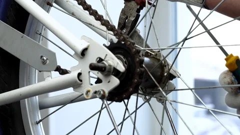 Installing the rear wheel in the bike frame. A repairman in white gloves fixes a Stock Footage 117800831