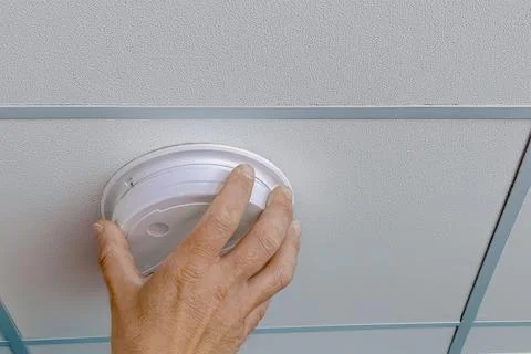 Installing smoke detector on ceiling panel Stock Photos