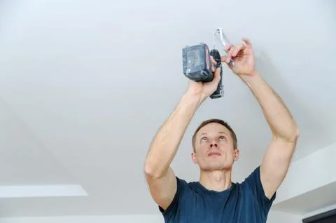 Installing a spotlight in the room. Stock Photos