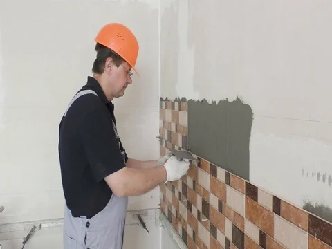 Installing tiles. The worker with the notched trowel. Stock Footage 79249736