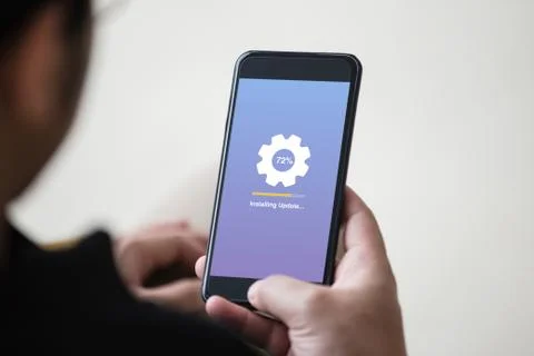 Installing update concept on phone screen. Man hand holding phone doing installi Stock Photos