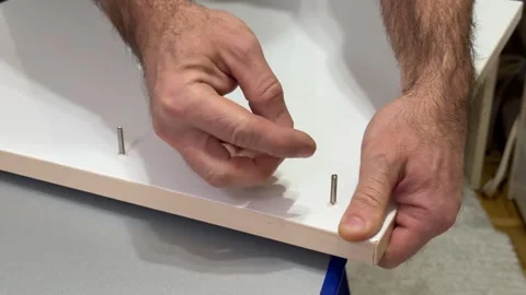 Installing upper board of shelf with wooden dowel pins in apartment closeup. Man Vídeos de archivo 323179470