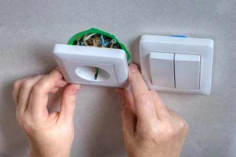 Installing the wall outlet into a wiring box, close-up hands. Stock Photos